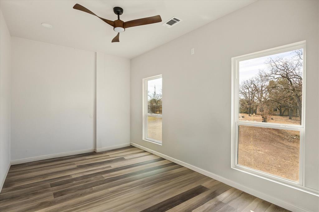 4801 West Wedgefield Road Granbury, TX 76049 - Photo 12 of 40 a view of empty room with wooden floor and fan