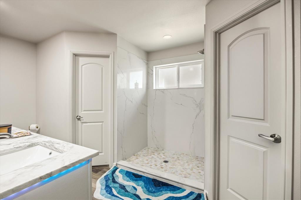 4801 West Wedgefield Road Granbury, TX 76049 - Photo 16 of 40 a bathroom with a sink a mirror and a shower