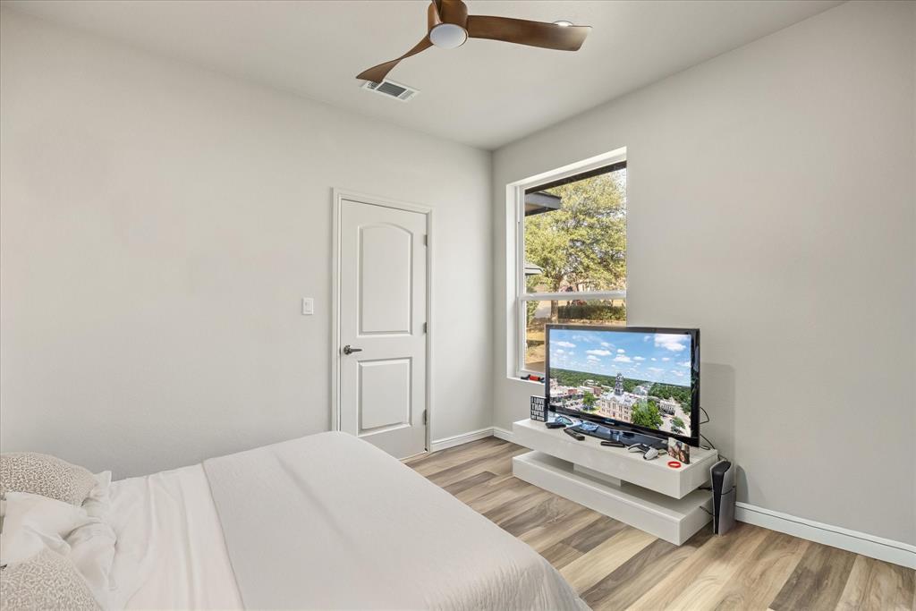 4801 West Wedgefield Road Granbury, TX 76049 - Photo 27 of 40 a bedroom with a bed window and a flat screen tv