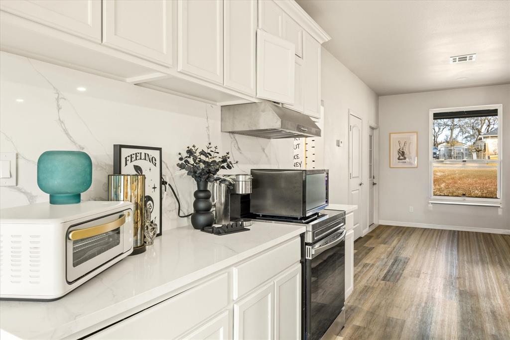 4801 West Wedgefield Road Granbury, TX 76049 - Photo 8 of 40 a kitchen with stainless steel appliances granite countertop a stove a microwave and a hard wood floor