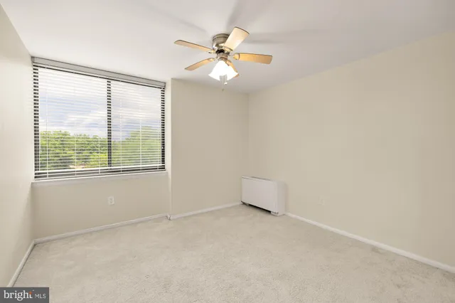 an empty room with a window and a fan
