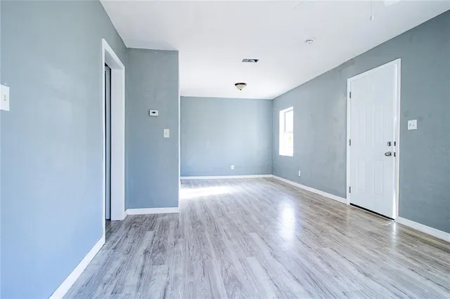 a view of an empty room with wooden floor and a window