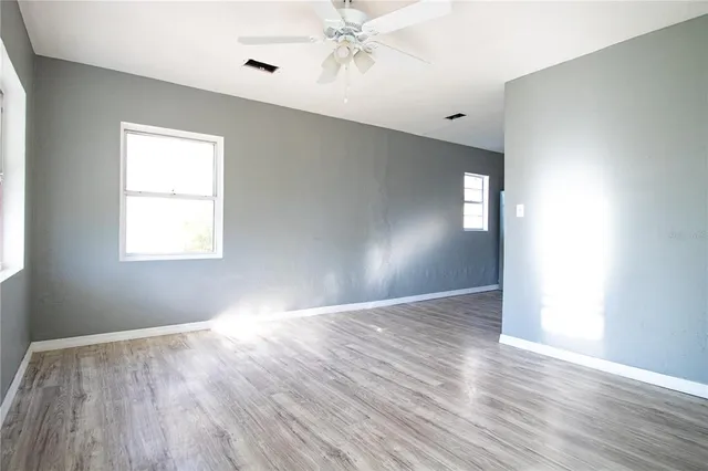 a view of an empty room with wooden floor and a window