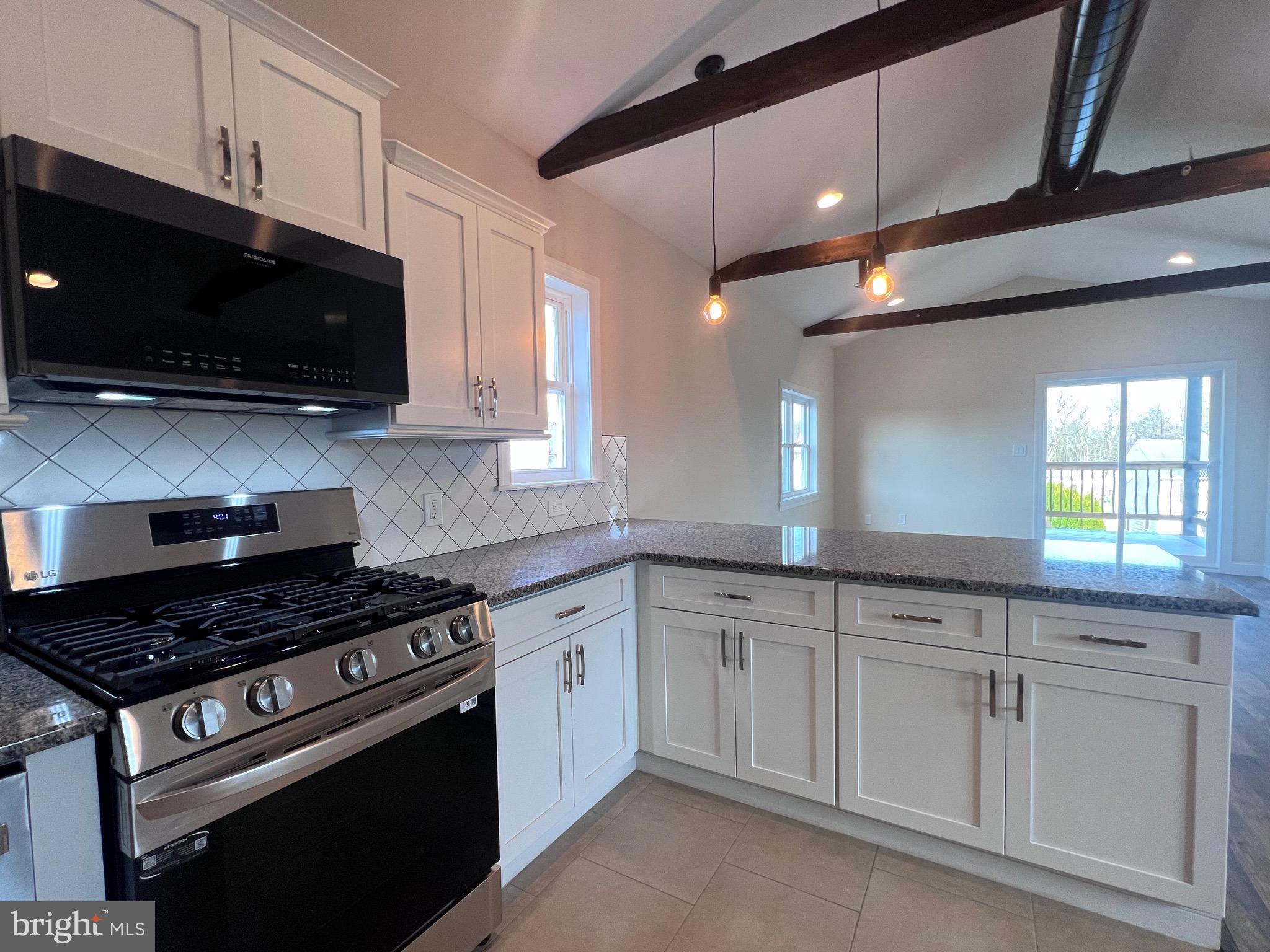 a kitchen with stainless steel appliances white cabinets granite counter tops and a window