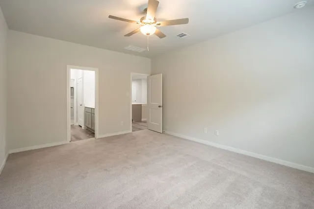an empty room with chandelier fan and windows