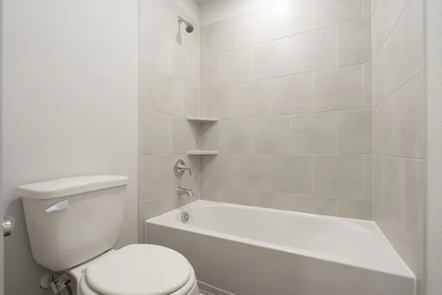a white toilet and tub sitting next to a bathroom sink