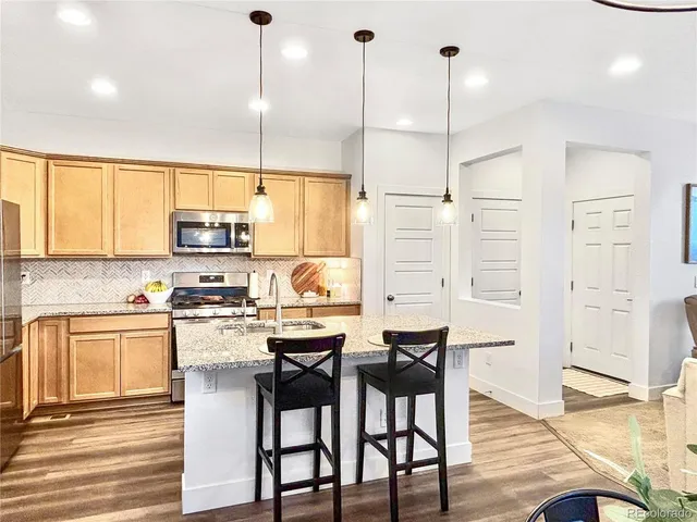 a kitchen with stainless steel appliances kitchen island granite countertop a stove a sink and white cabinets with wooden floor