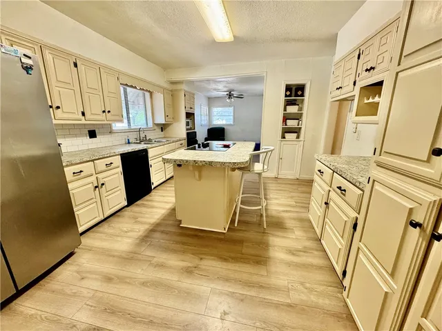 a large white kitchen with wooden floor and stainless steel appliances
