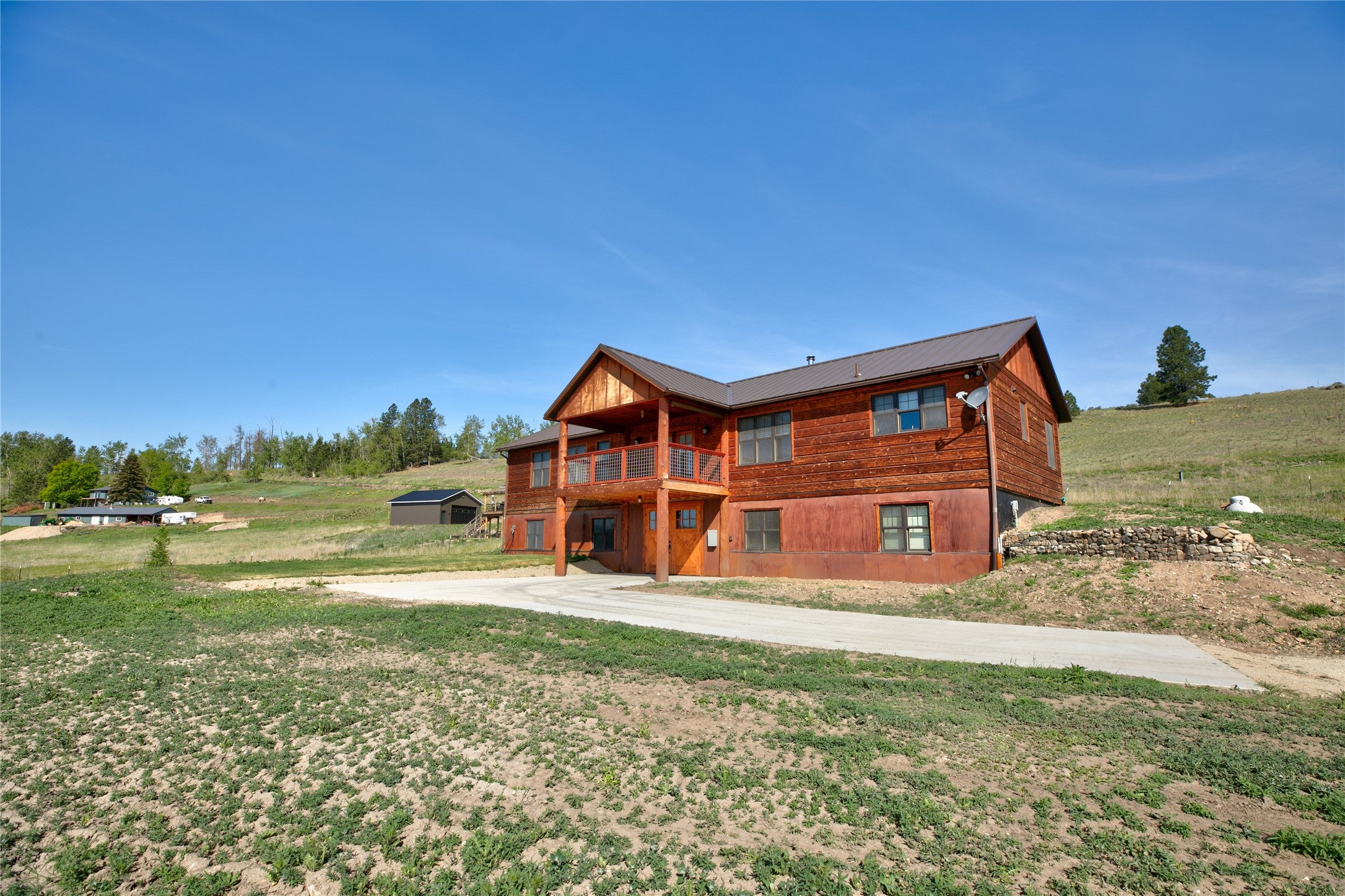 Front of the property with a balcony, a lawn, and metal roof