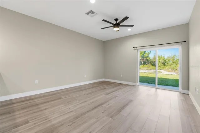 an empty room with wooden floor fan and windows