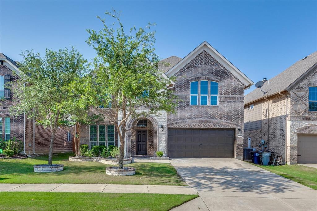 Brick and stone facade residence featuring an arched entryway, double front door, and an attached two-car garage