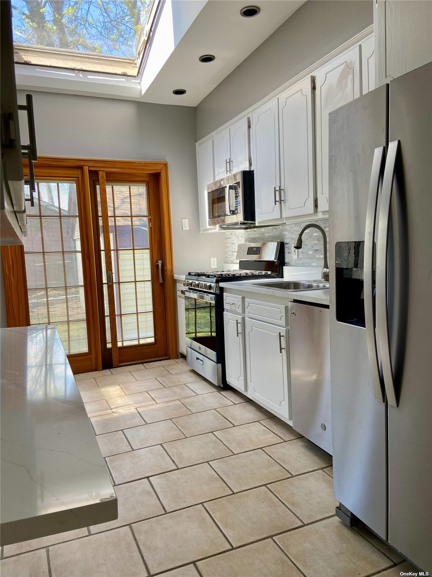 a kitchen with stainless steel appliances granite countertop a stove a sink a refrigerator and white cabinets