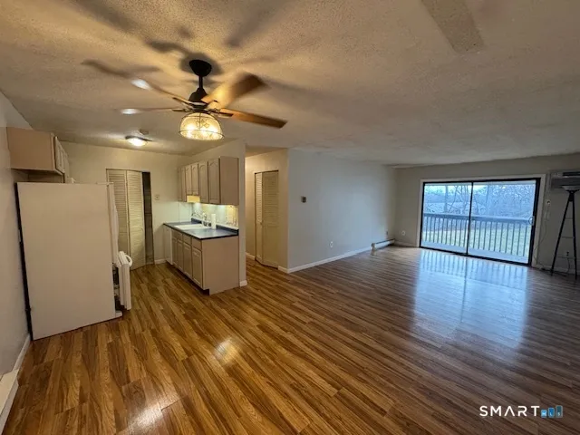 a view of an empty room with window wooden floor and a kitchen