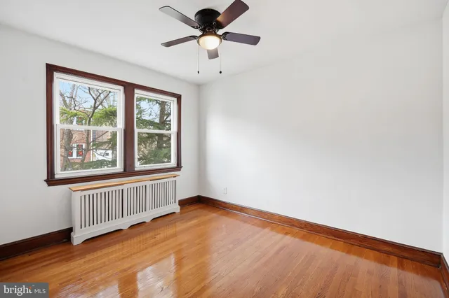 a view of an empty room with a window and wooden floor