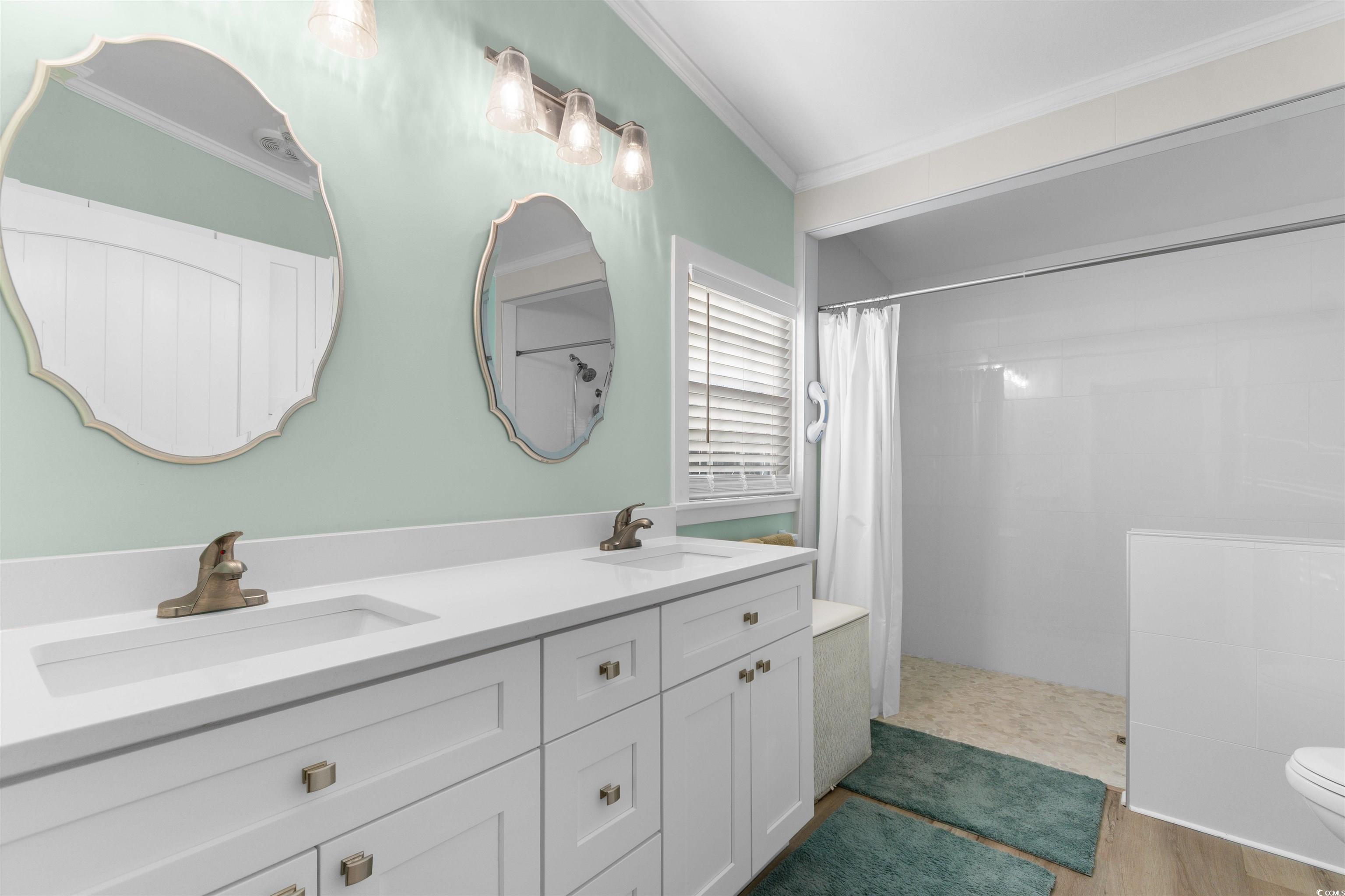 4065 Highway 66 Loris, SC 29569 - Photo 16 of 40 Bathroom featuring double vanity, a walk in shower, crown molding, and light wood-type flooring