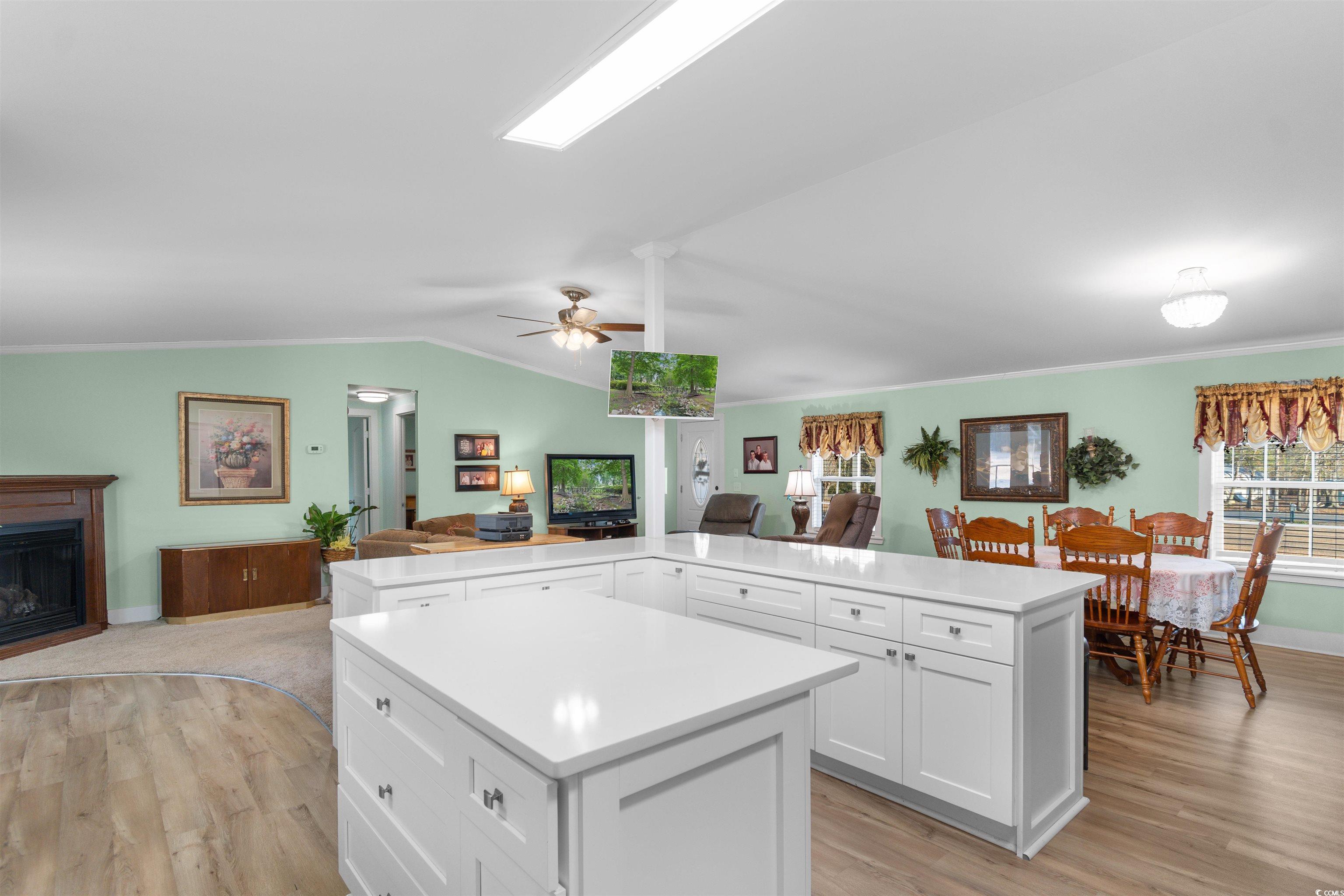 4065 Highway 66 Loris, SC 29569 - Photo 38 of 40 Kitchen with white cabinetry, open floor plan, light wood finished floors, vaulted ceiling, and crown molding