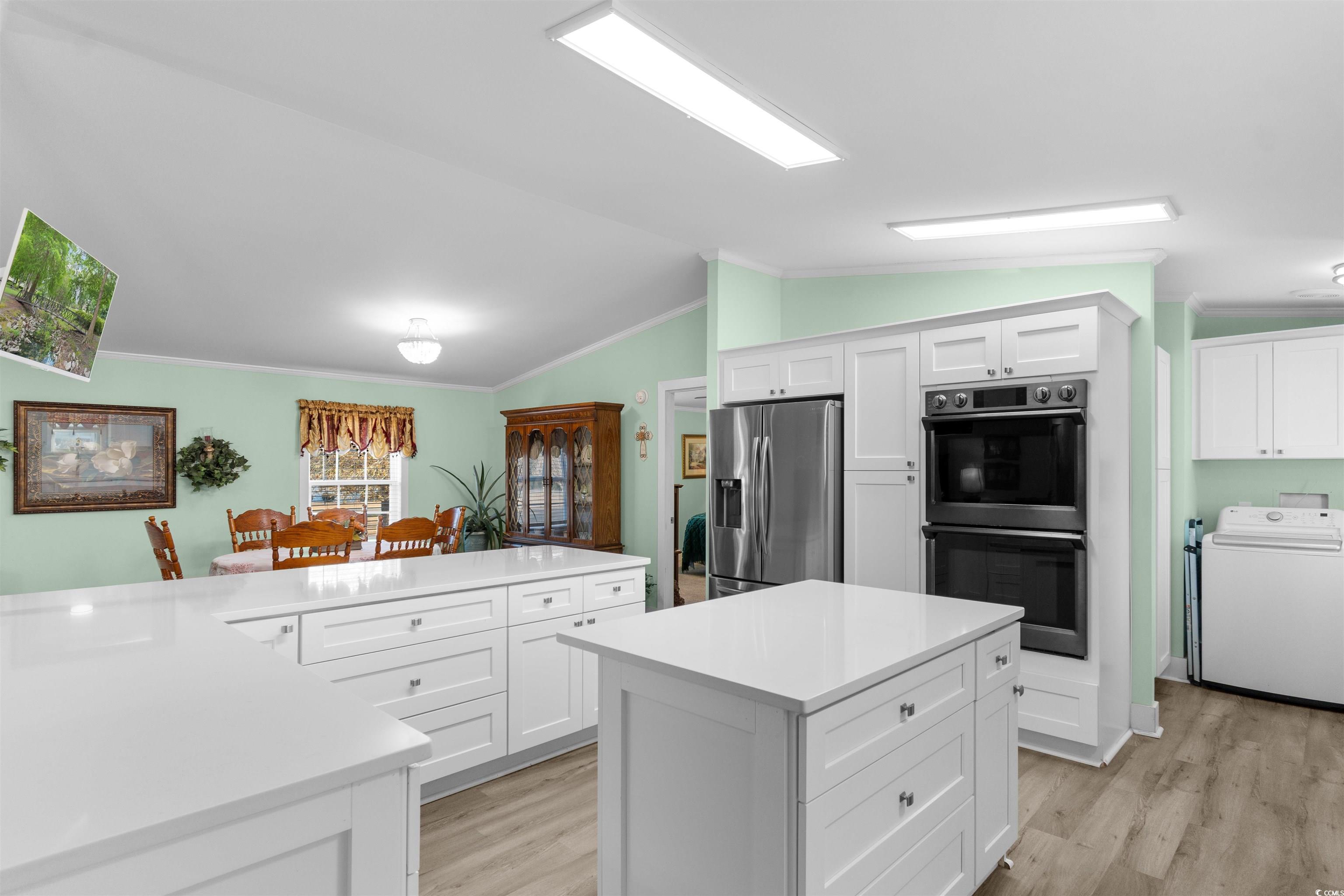 4065 Highway 66 Loris, SC 29569 - Photo 4 of 40 Kitchen featuring white cabinetry, stainless steel refrigerator with ice dispenser, washer / clothes dryer, lofted ceiling, and crown molding