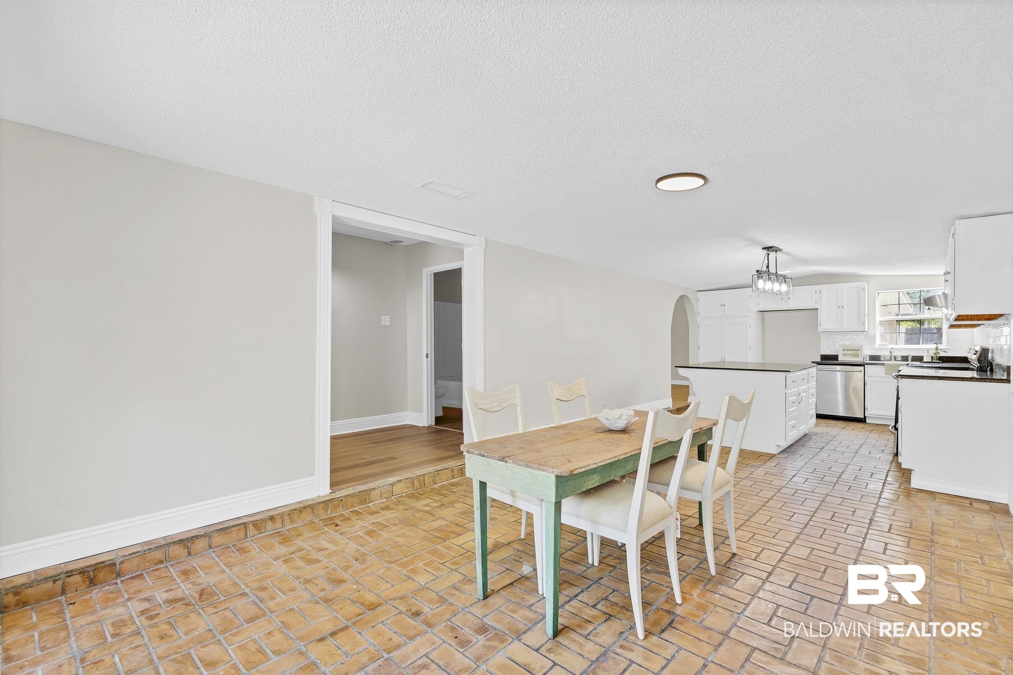 11964 Stroh Road Daphne, AL 36527 - Photo 20 of 58 Dining space featuring arched walkways, a textured ceiling, brick floor, baseboards, and a notable chandelier