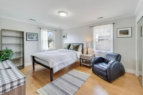 a bedroom with a bed couch and wooden floor
