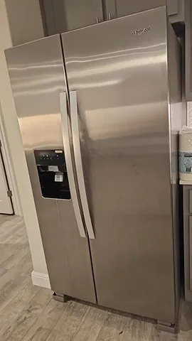 a walk in closet with wooden floor