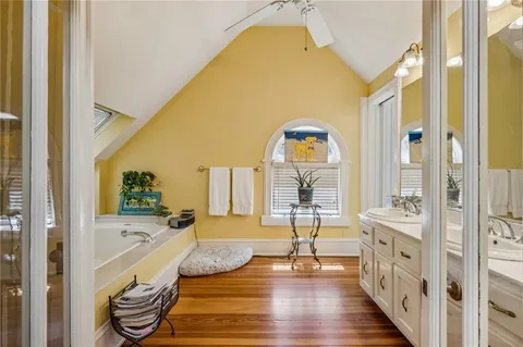 a spacious bathroom with a tub and a large mirror next to a window