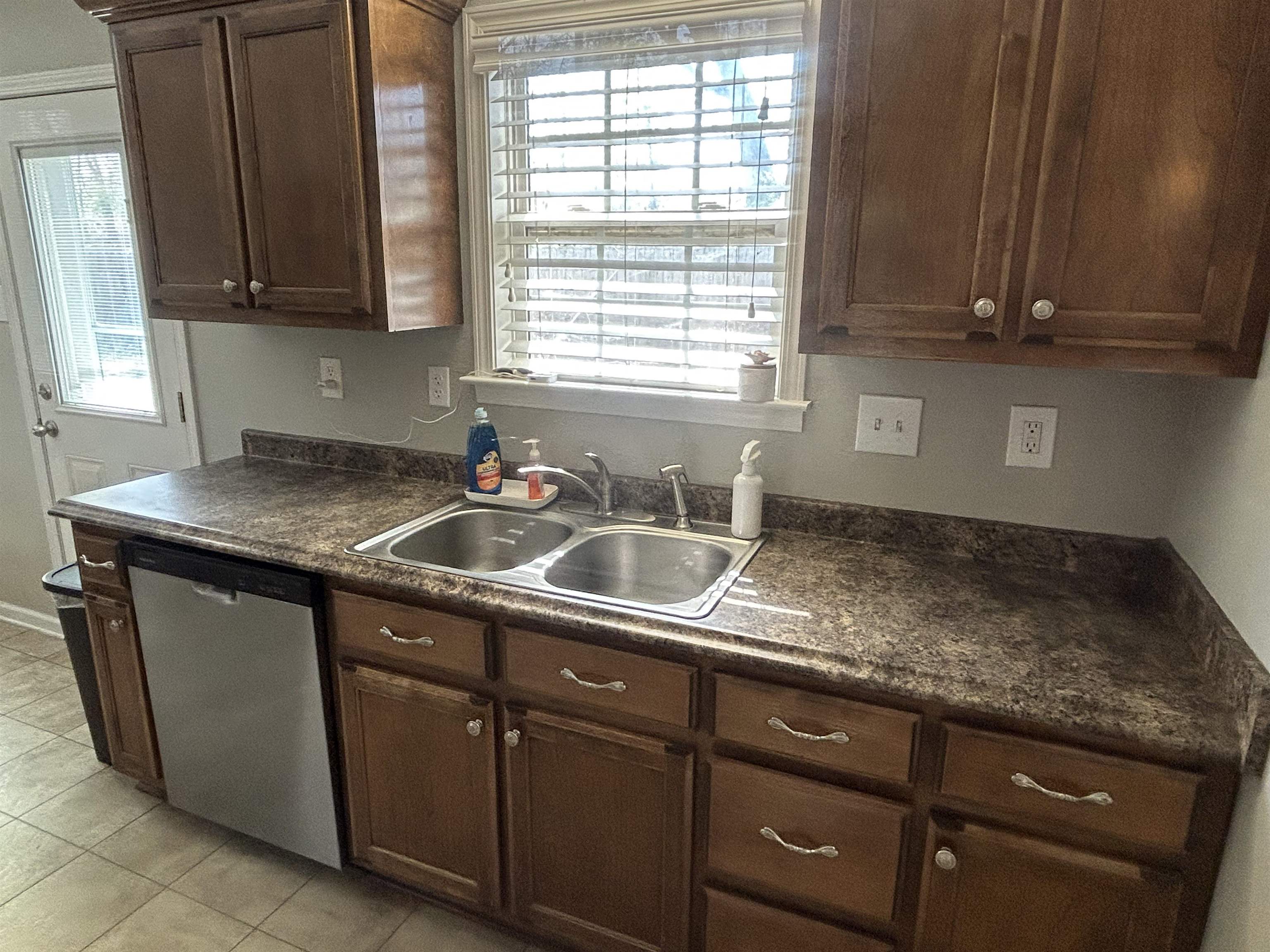 1535 Roane Street Covington, TN 38019 - Photo 24 of 25 Kitchen with dark countertops, dishwasher, dark wood finish cabinets, and light tile patterned floors