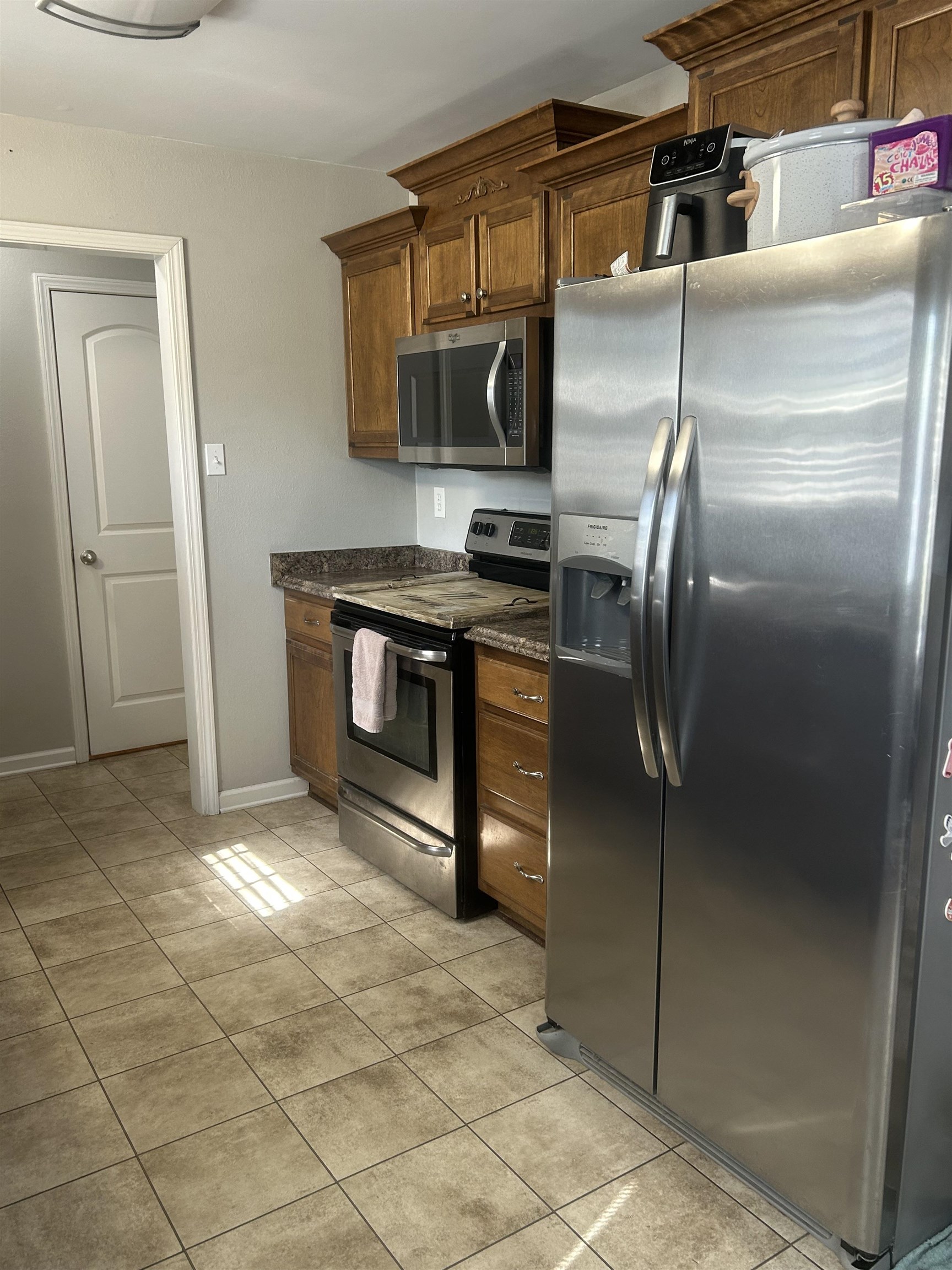 1535 Roane Street Covington, TN 38019 - Photo 5 of 25 Kitchen featuring stainless steel appliances, wood finish cabinetry, light tile patterned flooring, and dark stone countertops