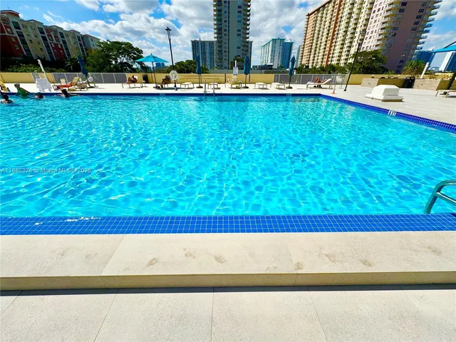 a view of a swimming pool with lawn chairs and wooden fence