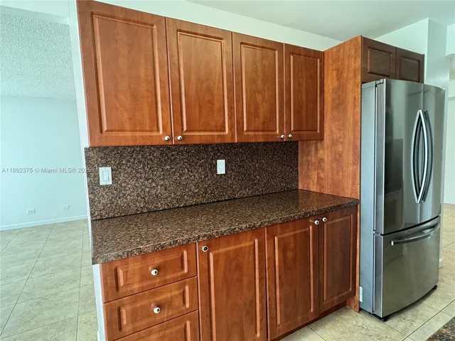 a kitchen with stainless steel appliances granite countertop a refrigerator and a wooden cabinets