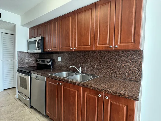 a kitchen with stainless steel appliances granite countertop a sink a stove and a microwave