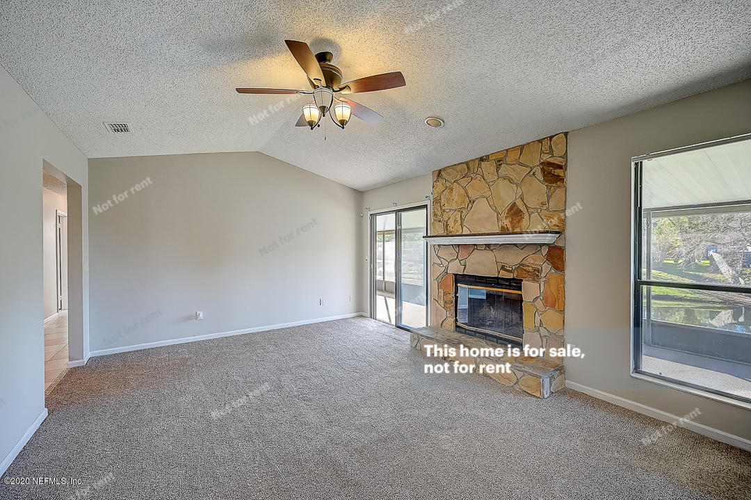 8864 Cherry Hill Drive Jacksonville, FL 32221 - Photo 12 of 17 a view of a livingroom with a fireplace a ceiling fan and windows