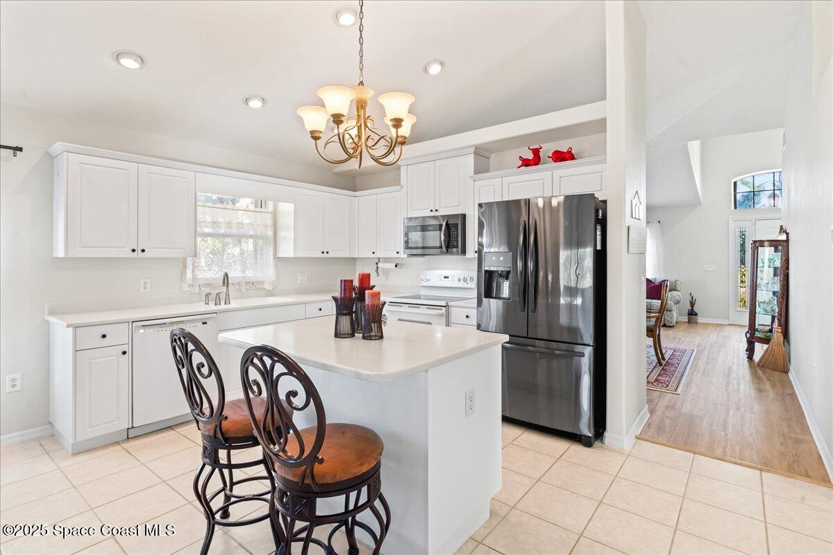 1404 Boca Rio Drive Melbourne, FL 32940 - Photo 17 of 53 a kitchen with stainless steel appliances granite countertop a refrigerator a sink dishwasher a dining table and chairs with wooden floor