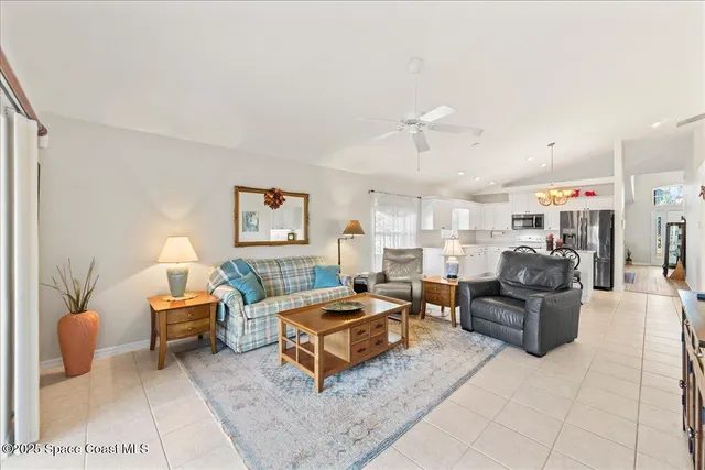 a living room with furniture a table and kitchen view