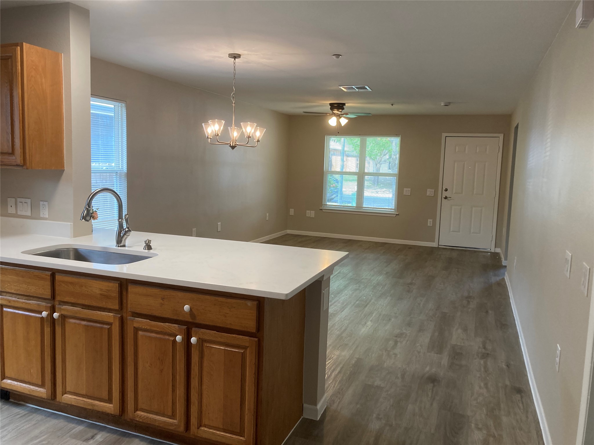 7307 Thannas Way Austin, TX 78744 - Photo 12 of 13 Kitchen featuring wood finish cabinets, a chandelier, a peninsula, and dark wood finished floors