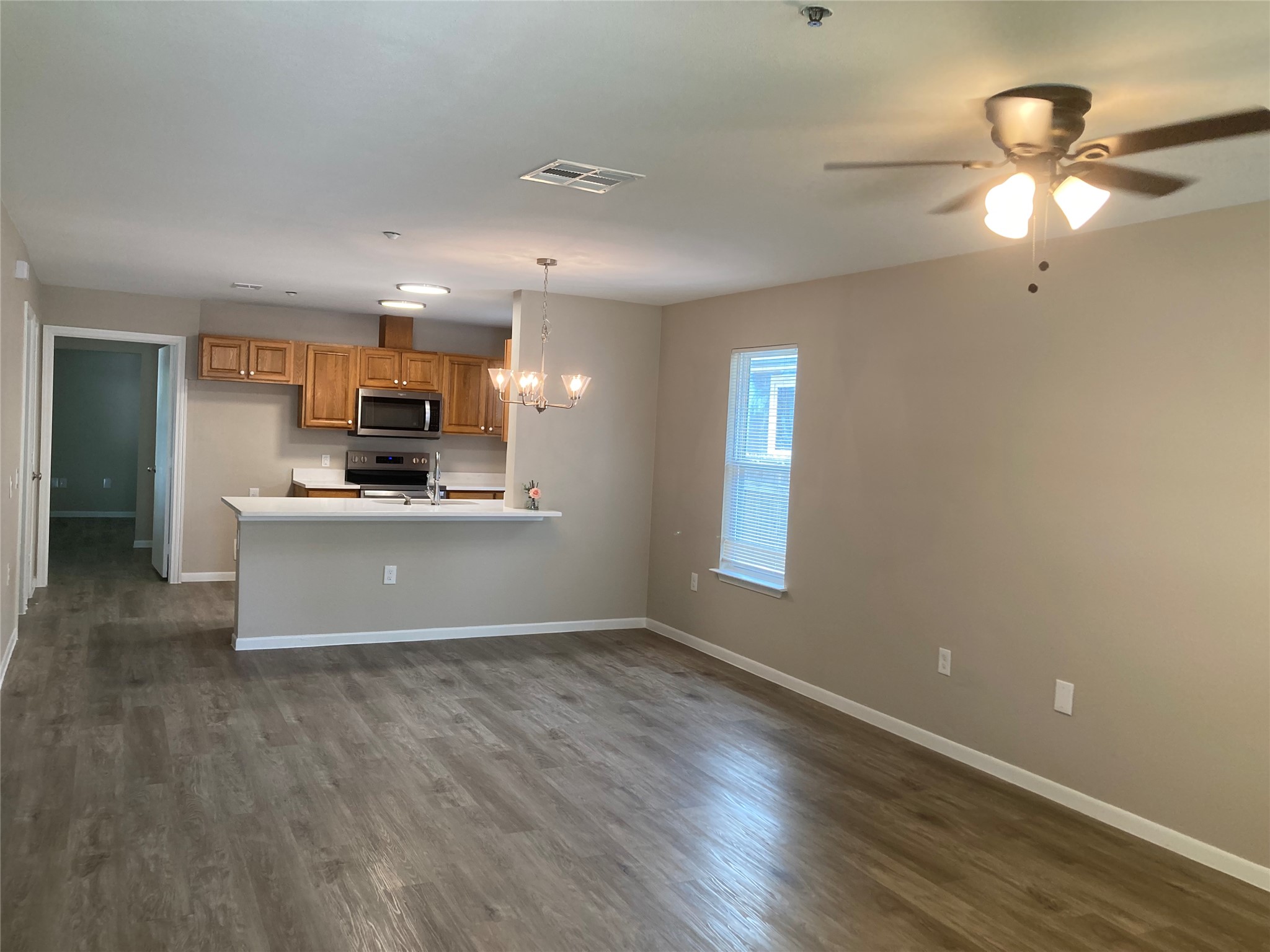 7307 Thannas Way Austin, TX 78744 - Photo 4 of 13 Kitchen with a chandelier, a peninsula, light countertops, and dark wood finished floors