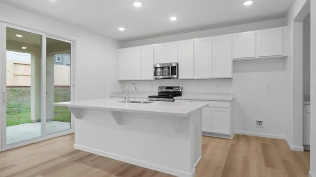 a kitchen with kitchen island a sink a stove a refrigerator and white cabinets