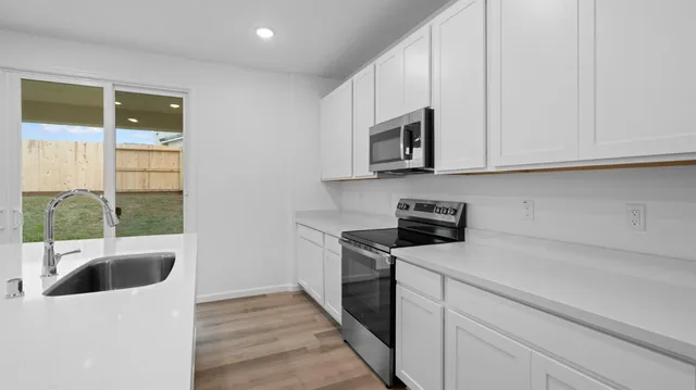 a kitchen with granite countertop a sink a stove and cabinets