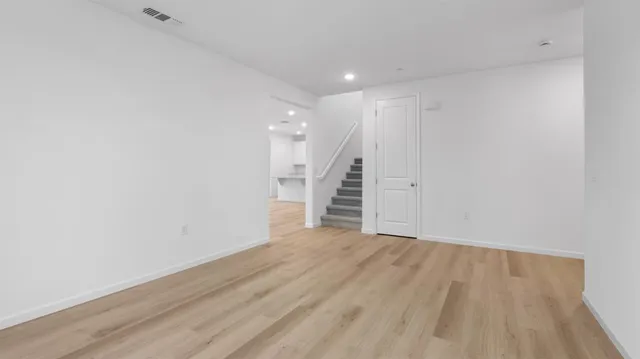 a view of an empty room with wooden floor and stairs