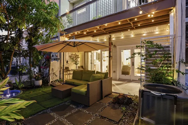 a view of a patio with couches table and chairs under an umbrella