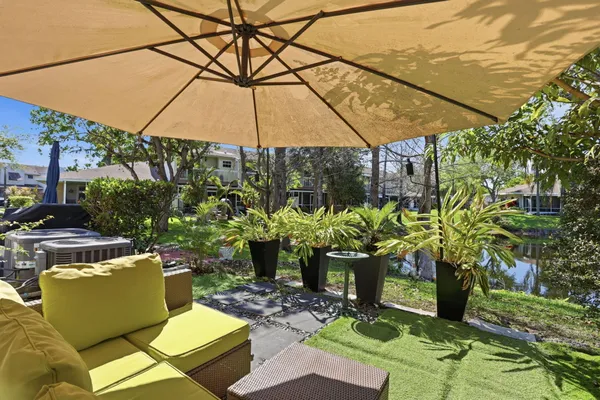 a view of a patio with couches table and chairs under an umbrella