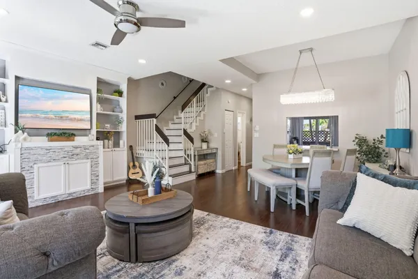 a living room with couches a dining table and a fireplace with wooden floor