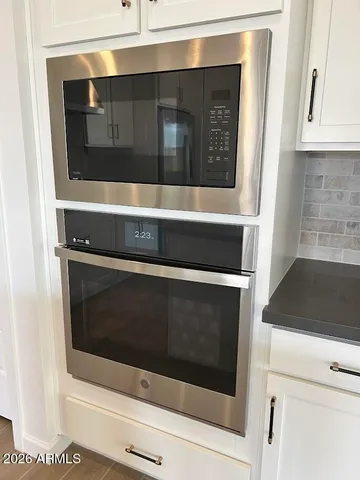 a kitchen with white cabinets and black appliances