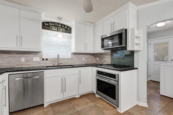 a kitchen with kitchen island a counter top space appliances and a view of living room