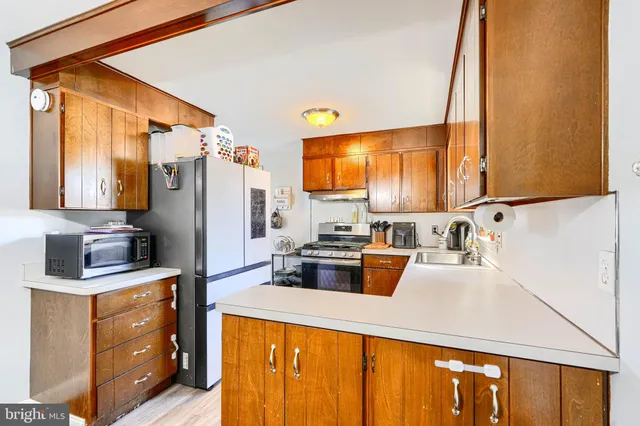 a kitchen with refrigerator a stove a sink dishwasher and wooden cabinets with wooden floor