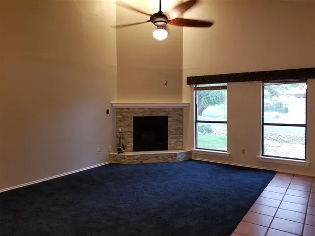 an empty room with windows and fireplace