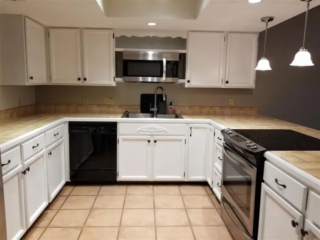 a kitchen with white cabinets appliances and sink