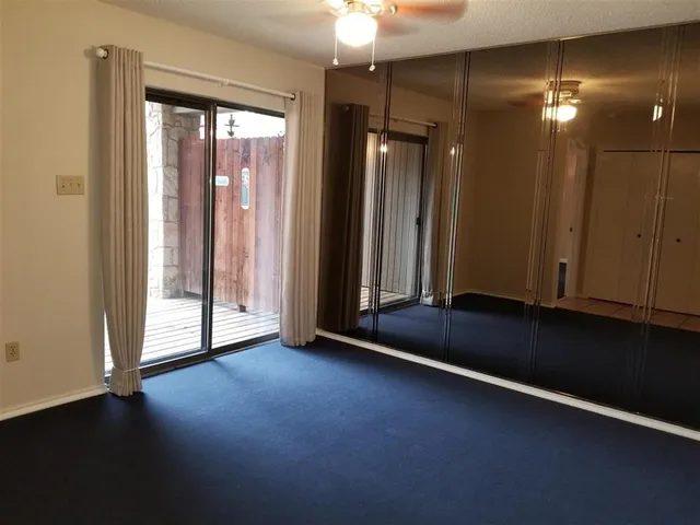 an empty room with wooden floor and windows with curtains