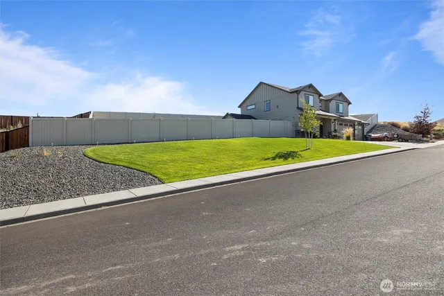 a front view of a house with yard and trees in the background