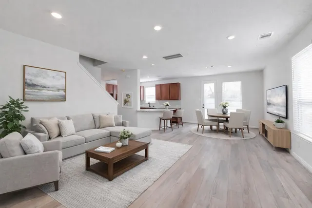 a living room with furniture and a flat screen tv with kitchen view