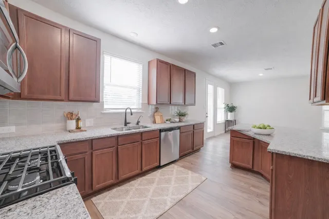 a kitchen with stainless steel appliances granite countertop wooden cabinets a stove top oven a sink and dishwasher